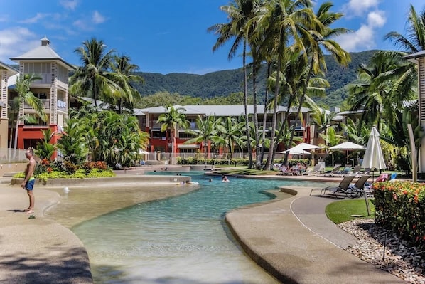 Un resort con piscina, palme e montagne sullo sfondo.