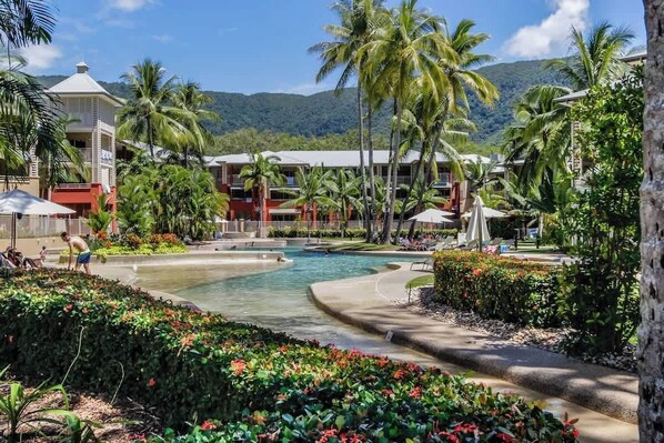 Un complexe hôtelier doté d’une piscine, de palmiers et offrant une vue sur les montagnes.