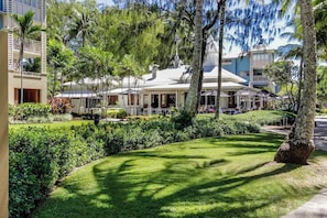 Un hotel con un'area salotto esterna coperta, immerso nel verde e con palme.