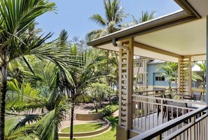Un balcón con vista a un jardín ajardinado y un edificio al fondo.