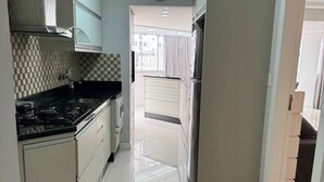 Una cocina con encimera negra, armarios blancos y un refrigerador de acero inoxidable.