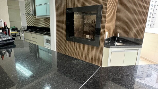 Una cocina moderna con encimera de granito negro, horno empotrado y salpicadero de azulejos.