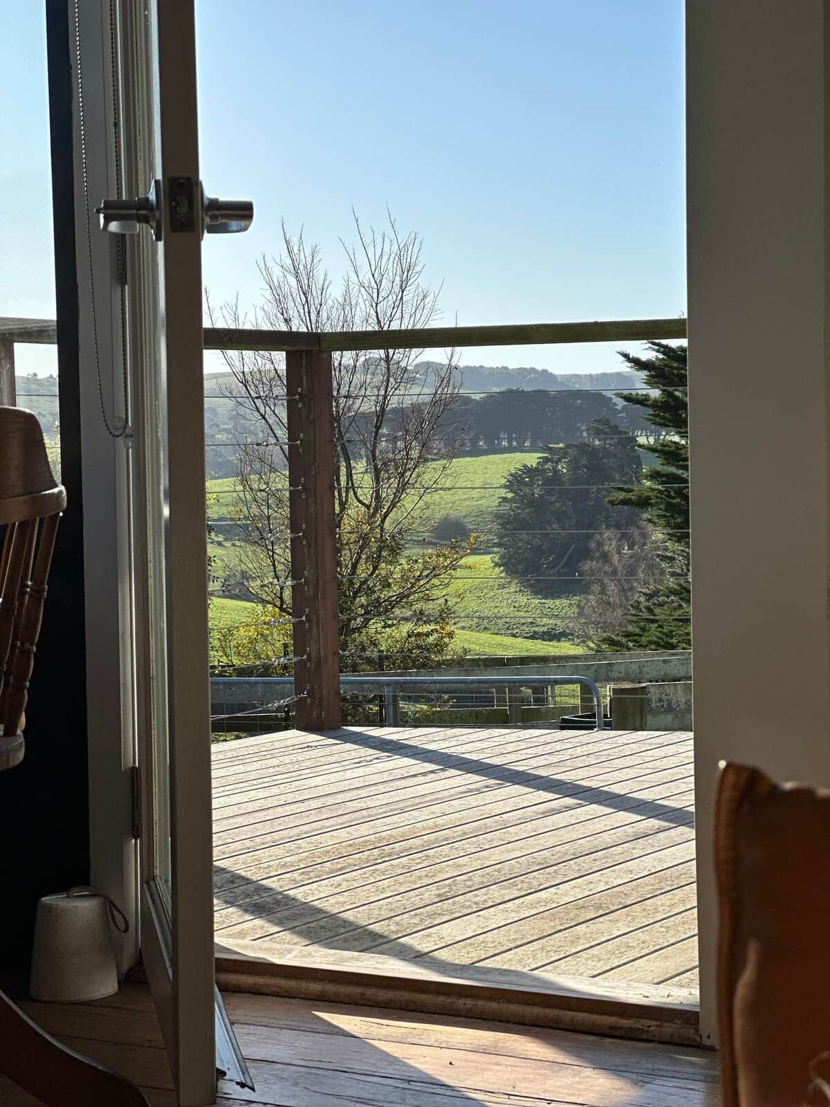 Eine Holzterrasse mit Blick auf eine grüne Landschaft und Hügel.