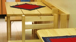A wooden table with a red placemat and a matching placemat on a chair. - Morabeza Kriol Hostel (Praia)