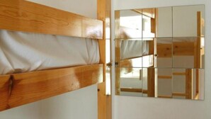 A wooden door with a white fabric panel, a mirror reflecting a room with wooden beams, and a white wall. - Morabeza Kriol Hostel (Praia)