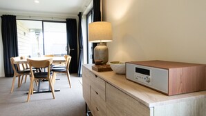 A hotel room with a dining area, a lamp, a radio, and a view of the outside.