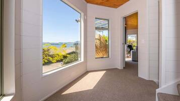 A spacious room with large windows offering a view of a lake and mountains, a wooden ceiling, and a carpeted floor.