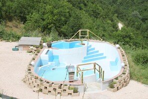 Ein runder Whirlpool mit einer Holzterrasse und einem kleinen Holzbau in der Nähe.