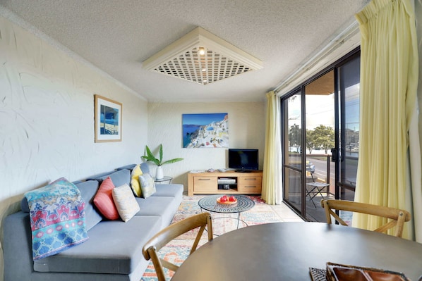 A living room with a sofa, TV, and dining table.