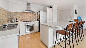 Una cucina moderna con mobili bianchi, un'isola centrale con sgabelli da bar, un piano cottura a gas e un forno integrato.