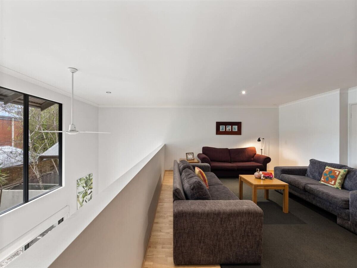 A modern living room with a sofa set, a coffee table, and a side table. There is a window providing a view of the outside.
