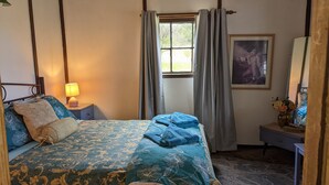 A bedroom with a bed, a nightstand, a window with curtains, a framed picture, and a small table with a vase. - Cathy's Cottage, Wuthering Heights ~ Dog friendly (Stanley Flat)