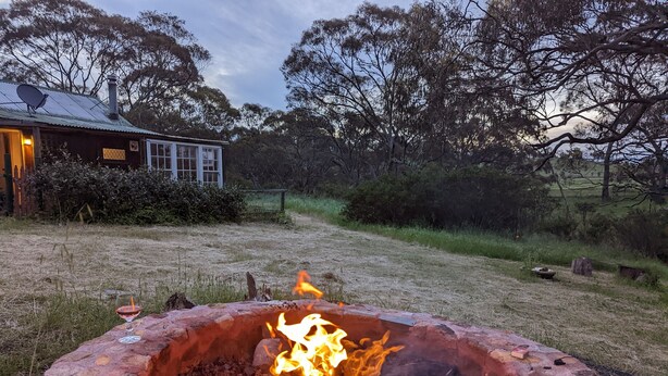 A stone fire pit with a glass of drink and a candle, surrounded by a grassy area and trees. - Cathy's Cottage, Wuthering Heights ~ Dog friendly (Stanley Flat)