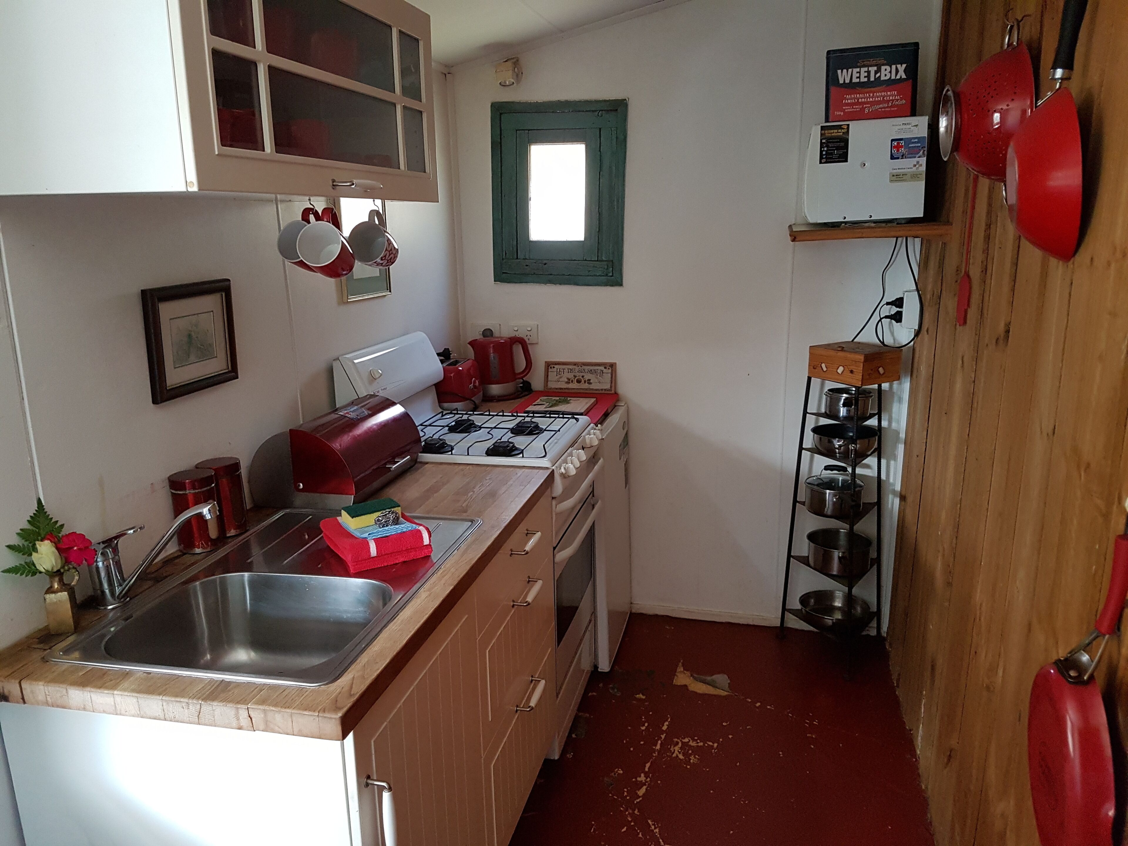A compact kitchen with a gas stove, a sink, and a window.