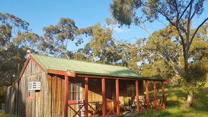 A rustic wooden building with a green roof, a porch with red railings, and a small window. - Cathy's Cottage, Wuthering Heights ~ Dog friendly (Stanley Flat)