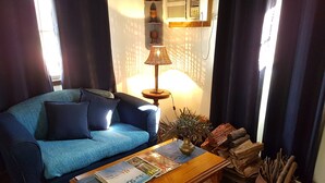A living room with a blue sofa, a wooden coffee table with a magazine, a lamp, and a vase with plants. - Cathy's Cottage, Wuthering Heights ~ Dog friendly (Stanley Flat)