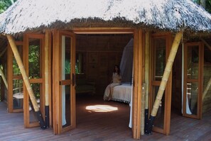 Une structure en bois avec un toit de chaume, un lit et une fenêtre.