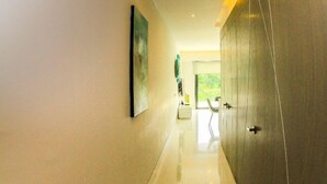 A modern hallway with a polished floor, a painting on the left wall, and a large wardrobe on the right. - Gris Coral st Calle 38 Condominium. Luxury one bedroom apartment next to beach. (Playa del Carmen)