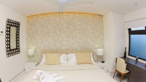 A hotel room with a large bed, two bedside tables, a desk with a chair, and a large window. - Gris Coral st Calle 38 Condominium. Luxury one bedroom apartment next to beach. (Playa del Carmen)