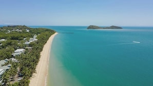 Paesaggio costiero con spiaggia, molo e una piccola isola.