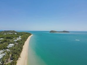 Paesaggio costiero con spiaggia, molo e una piccola isola.