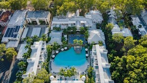 Una vista aerea di un resort con una piscina centrale, diversi edifici e una spiaggia.