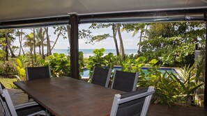 An outdoor dining area with a view of the ocean and a pool. - Gecko's Cottage - Absolute Beachfront (Mission Beach)