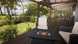Un espacio de estar techado al aire libre con vista al océano y una piscina.