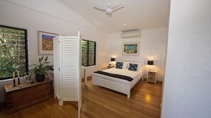 Una camera da letto con un letto, comodini, una ventola a soffitto e una finestra con persiane.
