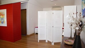 Una stanza con una parete rossa a contrasto, una porta bianca e un pavimento in legno.