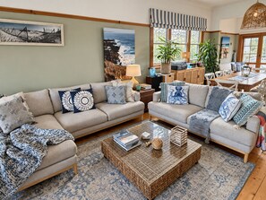 A living room with two sofas, a coffee table, and a dining area with chairs and a table.