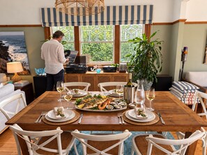 Un coin repas avec une table en bois dressée pour le repas, entourée de chaises blanches.