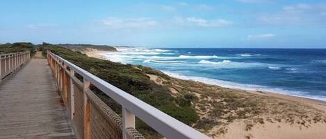 A wooden boardwalk leading to a beach with ocean views.