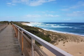 A wooden boardwalk leading to a beach with ocean views.
