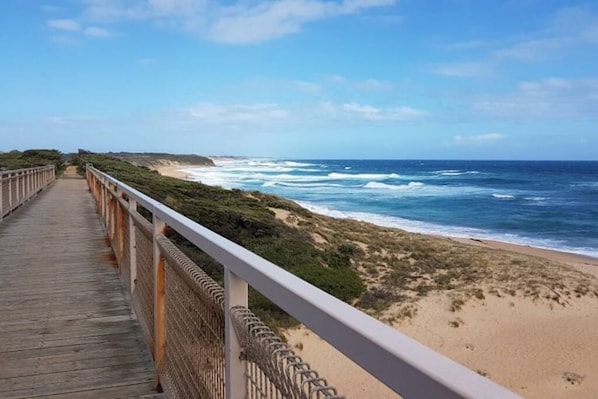 A wooden boardwalk leading to a beach with ocean views.