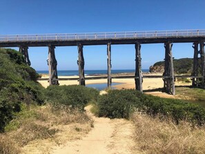 A wooden bridge over a beach with a clear sky.