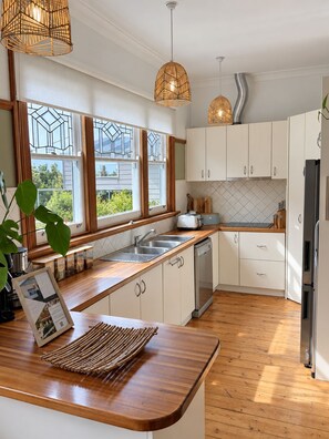 A modern kitchen with white cabinets, a wooden countertop, and a built-in dishwasher.