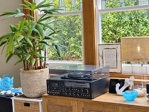 A room with a large window, a potted plant, a turntable, and various decorative items.