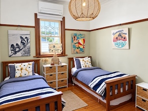A bedroom with two wooden beds, a window with a view, and wall decorations.