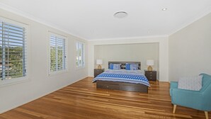 Un dormitorio amplio con una cama grande, dos mesitas de noche y una silla.