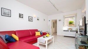 Un salon moderne avec un canapé rouge, une table basse blanche et un meuble vitré.