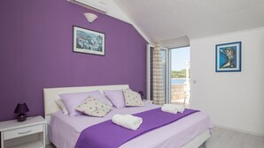 Une chambre à coucher avec un grand lit, des murs violets et deux tableaux encadrés.