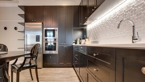A modern kitchen with dark cabinetry, stainless steel appliances, and a white countertop. - Family Retreat In Top Blue Mountains Location (Katoomba)