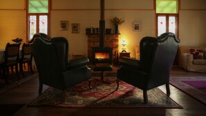 A cozy living room with two leather armchairs, a fireplace, and a dining area with a table and chairs.