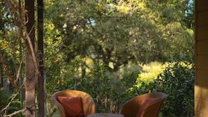 A wooden deck with wicker furniture and a view of lush greenery.