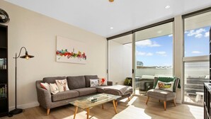 A modern living room with a sofa, a glass coffee table, and a bookshelf.