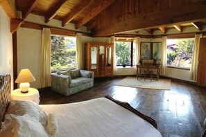 A spacious bedroom with a large bed, a sitting area with a sofa and a table, and multiple windows offering views of the outdoors. - Casa los Cuatro Manguitos for 10 guests 5 min away from lake & downtown (Valle de Bravo)