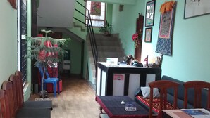 A spacious living area with a wooden bench, a reception desk, and a staircase leading to an upper floor.