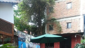 An outdoor seating area with tables and chairs, surrounded by potted plants and a mural.