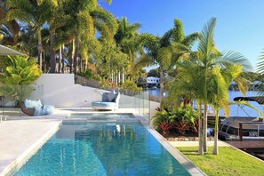 A swimming pool with lounge chairs and palm trees. - The Peninsula Secret (Noosaville)